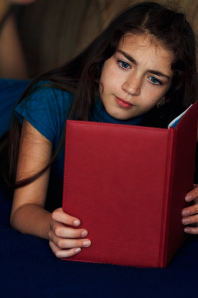 女孩躺在床上看书图片下载