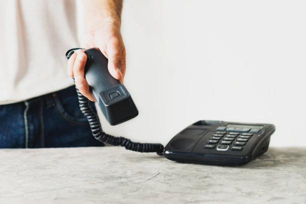 男子手持手机靠近水泥桌子，白色背景上的旧电话。通信的概念。本空间图片下载