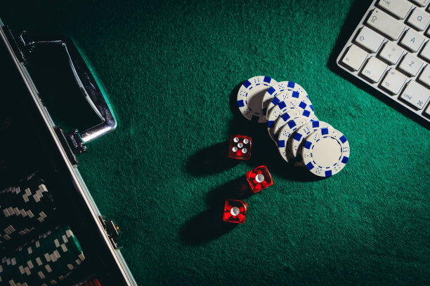 网上赌博的概念。俯视图手提箱扑克，筹码，骰子和键盘上的桌子图片下载
