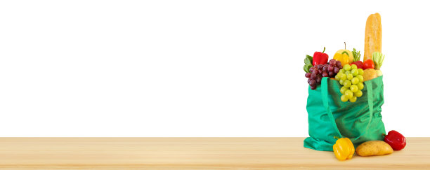 新鲜的水果和蔬菜杂货产品在绿色可重复使用的购物袋上木质桌面孤立在白色的背景图片下载