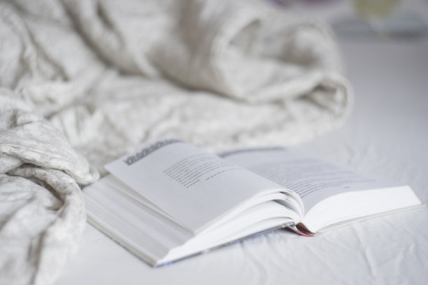 在床上看书，平静舒适的早晨心情照片，灰色和米色的毯子和床单。家庭生活方式图片下载