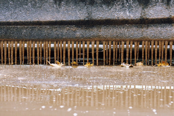 一辆车停在肮脏的水坑里，冬天解冻了，门前的台阶上挂着冰柱图片下载