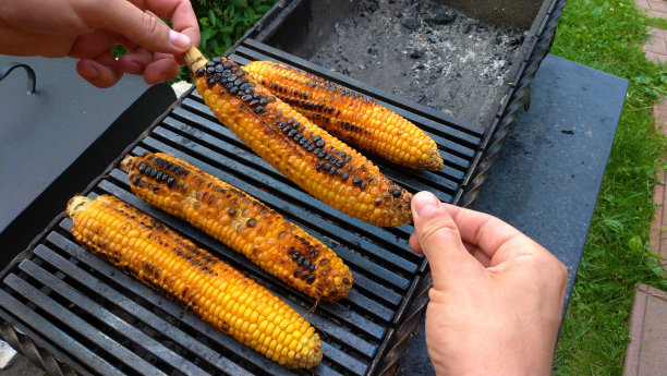 用火烤的烤玉米。在一张深色的铁桌上。烤玉米。美味的街头食品。夏日派对和烧烤。手拿或握住烤玉米图片下载