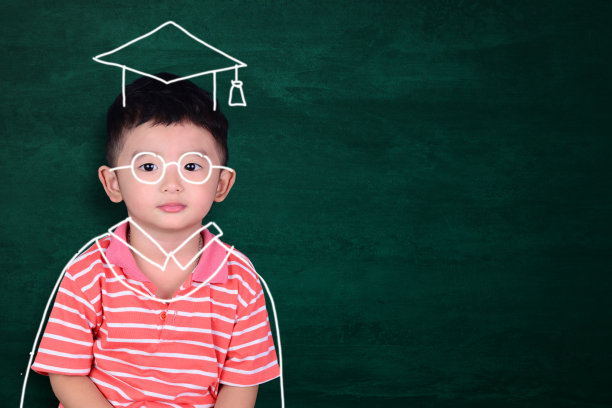 亚洲孩子想象他的毕业日与手绘毕业服装在绿色黑板的背景，教育和毕业概念。图片下载
