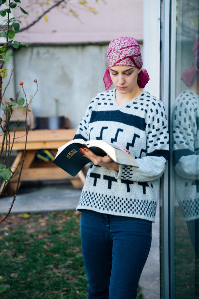 生病的女孩站在窗边读圣经图片下载