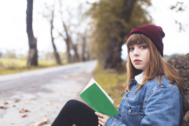 年轻女子在森林的路上看书图片下载