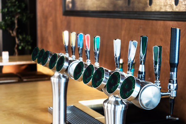 木墙背景上的一排啤酒分发器。图片下载