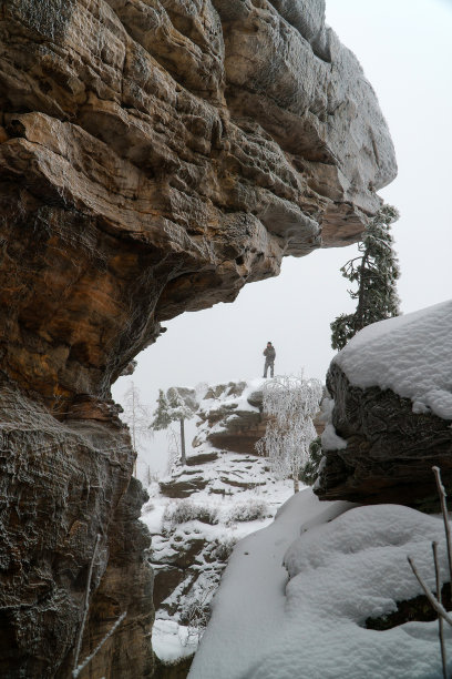 男子站在岩石上在冬季著名的国家公园石城，俄罗斯，彼尔姆地区。图片下载