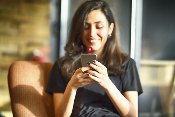 年轻女子使用带有社交媒体符号的智能手机图片下载