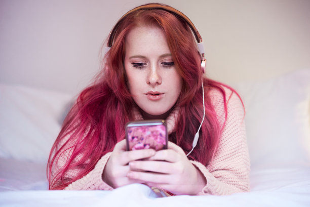 小女孩戴着耳机看手机图片下载