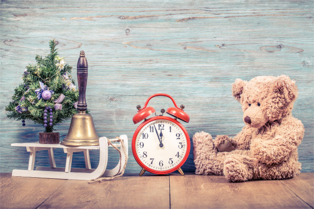 新年树，泰迪熊玩具，青铜钟，复古钟和木制雪橇前纹理墙背景。圣诞贺卡的概念。复古instagram风格过滤照片图片下载
