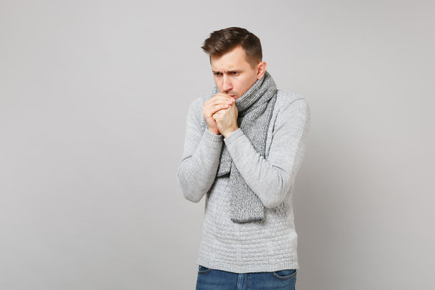 冰冷的年轻人穿着灰色毛衣，围巾吹着，温暖的手孤立在工作室的灰色墙壁背景。健康时尚的生活方式，人们真诚的情感，寒冷的季节理念。模拟拷贝空间。图片下载