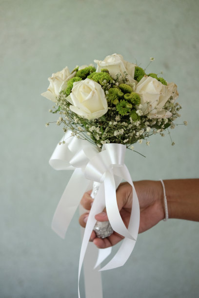 一位新娘手持她美丽的白玫瑰花束图片下载