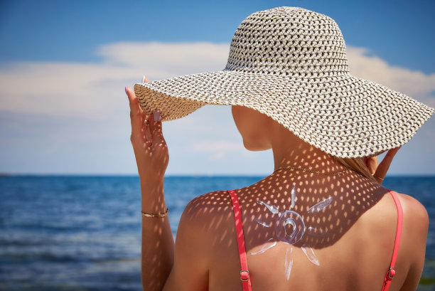 戴着帽子的女孩，背上涂着太阳形状的防晒霜。图片下载
