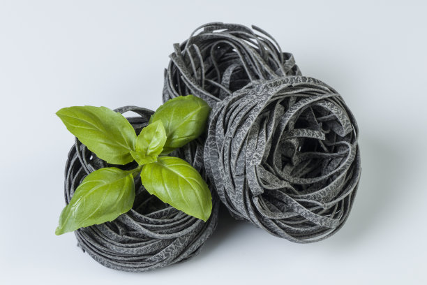 生意大利面与罗勒叶孤立在白色。图片下载