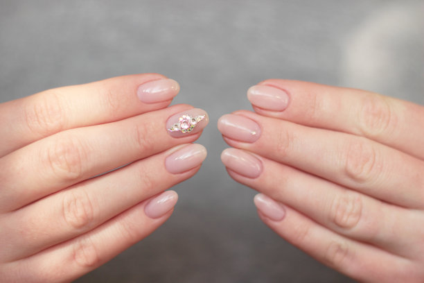 双手温柔的裸粉色美甲与水钻在中指接近图片下载