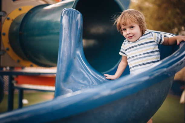 在游乐场滑滑梯的可爱小男孩图片下载