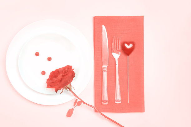 2019年潘顿色——活珊瑚。顶视图浪漫的桌子设置情人节晚餐约会庆祝婚礼与玫瑰花蕾盘子在桌布珊瑚色背景。健美的图片下载