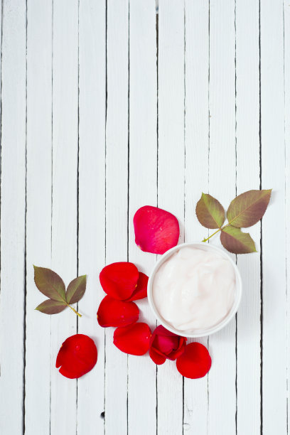 化妆品霜，红玫瑰花瓣，白木桌图片下载