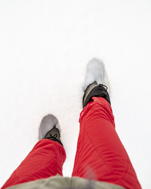 在寒冷的一天，穿着暖靴的人腿站在雪堆里图片下载