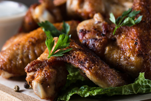 烧烤鸡翅与薯条和啤酒的特写照片。烤肉配酱汁，番茄酱，蛋黄酱。快餐和垃圾食品的概念。图片下载