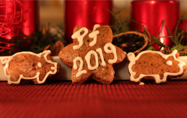 自制姜饼星覆盖白色糖霜和字母PF 2019。两边有两只姜饼猪。在背景圣诞烛台图片下载