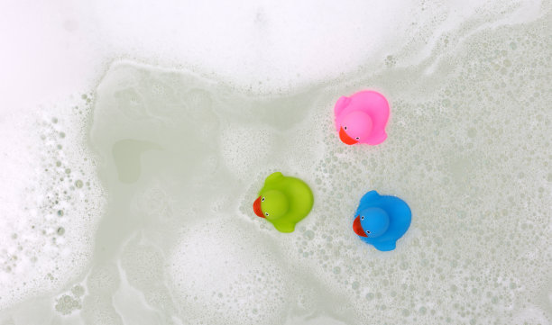 粉红色、绿色和蓝色的鸭子在浴缸里图片下载