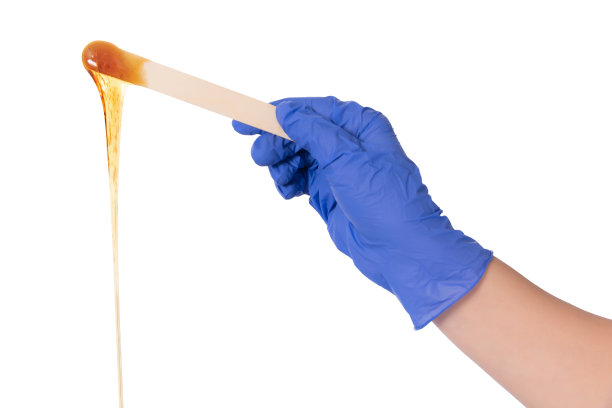 美容师戴着蓝色手套，手里拿着刮刀打蜡图片下载