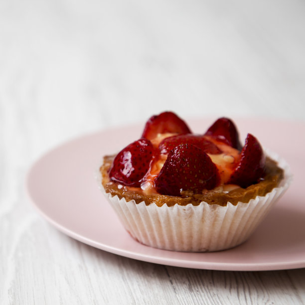 粉色盘子上的草莓香草奶油芝士挞，侧视图。特写镜头。白色木制背景。图片下载