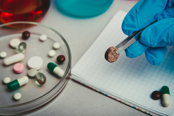 持有药丸的背景化学实验室和试剂。非法药丸，药品生产在实验室。药物发现。药理学和生物技术概念图片下载