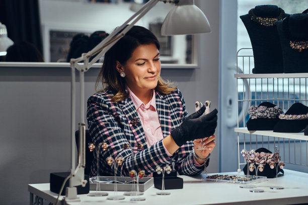 在一家豪华珠宝店里，女珠宝工人正在展示镶有宝石的漂亮的珍贵耳环。图片下载