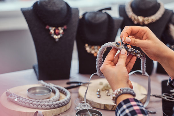 特写照片的一个女人的手谁制作手工项链。图片下载