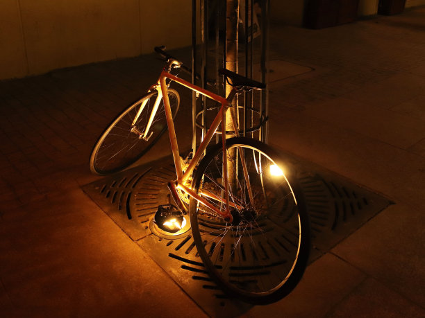 傍晚的时候，这辆自行车斜靠在古城中心的一棵树上。生态交通。健康的生活方式是长寿的秘诀。夜晚街道的照明。图片下载