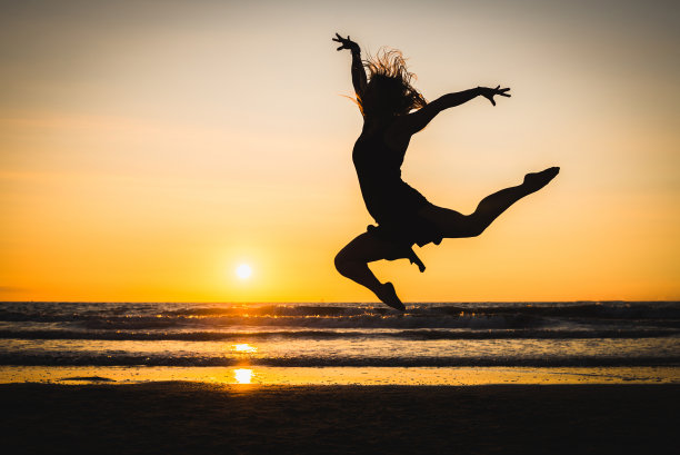 夕阳下一个快乐美丽的舞女的剪影图片下载