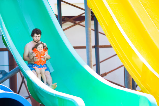 快乐的家庭在一起玩水上滑梯在户外游泳在水上公园(水上公园)图片下载