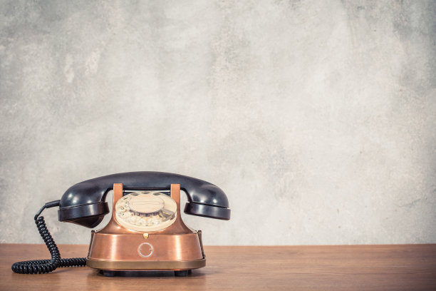 复古、古典、过时的铜与黑色旋转电话，大约来自20世纪50年代木桌前纹理混凝土墙背景。复古instagram老风格滤镜照片图片下载