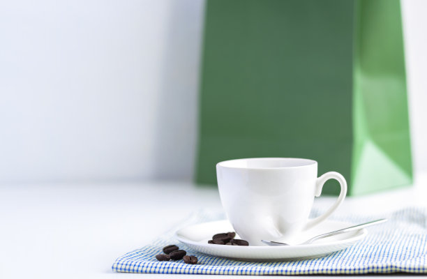 亮蓝色的布上放着一杯白咖啡和一个纸袋。通过喝咖啡来放松的概念。图片下载