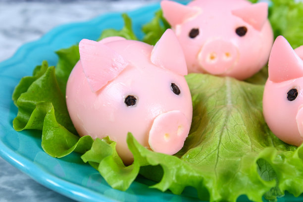 用鸡蛋做猪。制作猪的工作坊，将煮鸡蛋涂在肉汤里，并填上甜菜馅。圣诞或新年餐桌上的开胃菜。前视图。创意儿童装饰食品。素材图片