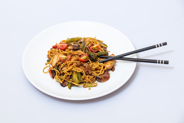 锅里的食物放在一个白色的陶瓷盘子里，配上酱汁，在一个明亮的孤立的背景下，味道鲜美图片下载