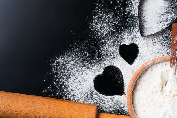烘烤背景用面粉、擀面杖和心形放在有拷贝空间的深色桌子上，俯视图，平铺。情人节烹饪概念图片下载