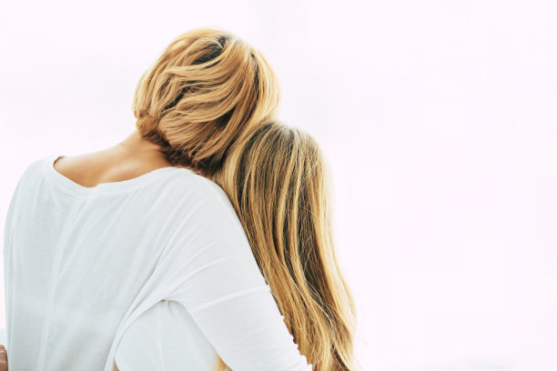 后视图照片美丽的年轻母亲和她的小女儿坐在床上的白色窗户的背景图片下载