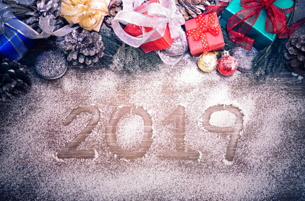白雪覆盖在松果上，背景是金色和红色的球和红色的礼盒，雪的中心有文字2019素材图片