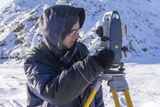 测量师冬天在建筑工地进行测量工作图片下载