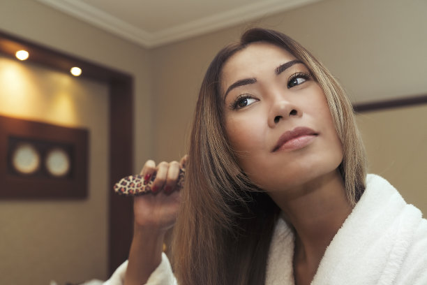 亚洲妇女梳头用梳子在酒店房间图片下载