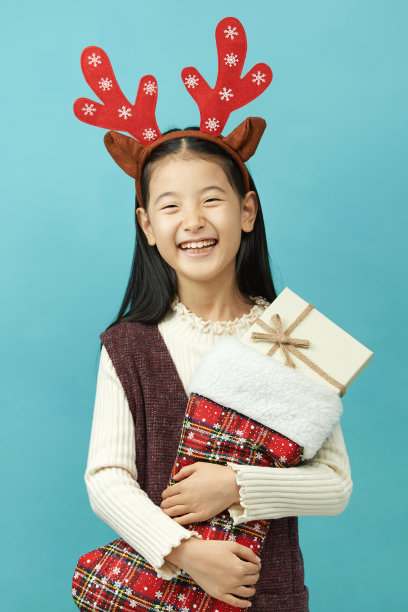 亚洲女孩与圣诞节概念头饰儿童，近距离可爱的小亚洲女孩在蓝色背景孤立图片下载