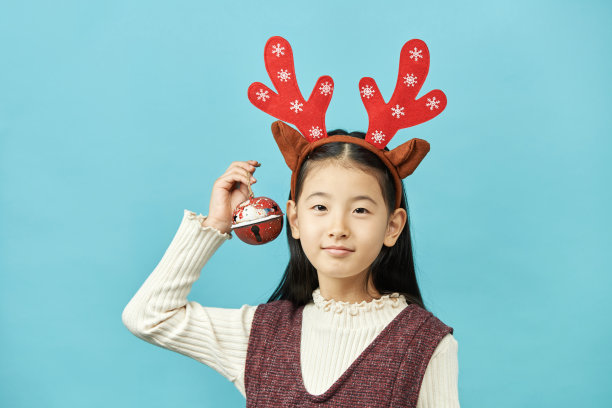 亚洲女孩与圣诞节概念头饰儿童，近距离可爱的小亚洲女孩在蓝色背景孤立。图片下载
