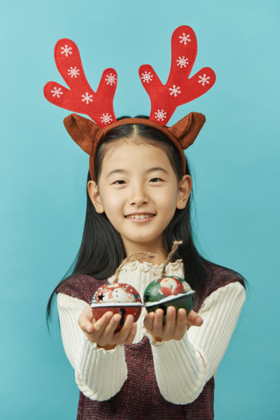 亚洲女孩与圣诞节概念头饰儿童，近距离可爱的小亚洲女孩在蓝色背景孤立。图片下载