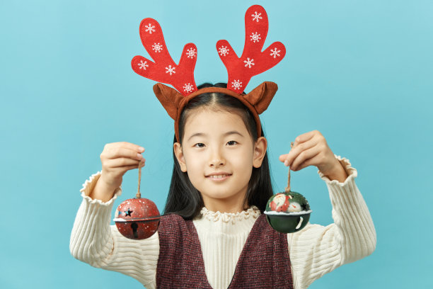 亚洲女孩与圣诞节概念头饰儿童，近距离可爱的小亚洲女孩在蓝色背景孤立。图片下载