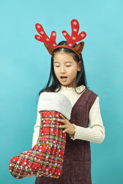 亚洲女孩与圣诞节概念头饰儿童，近距离可爱的小亚洲女孩在蓝色背景孤立图片下载
