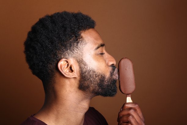 一个棕色背景前拿着冰淇淋的漂亮黑人图片下载